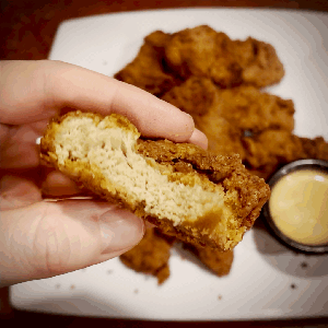 A gif showing vegan kfc-style fried chicken bitten into and tearing to showcase vegan chicken-like texture. 